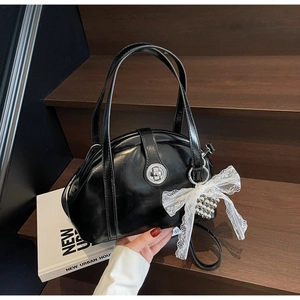 Détail du sac à main noir verni avec fermoir argenté et breloque en dentelle