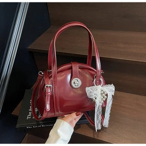 Détail du sac à main bordeaux verni avec nœud en dentelle et fermoir rotatif argenté