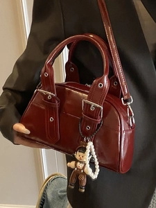 Deep red shiny leather Boston bag with decorative silver buckles and pearl charm