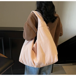 Borsa tote a mezzaluna rosa tenue in nylon morbido sulla spalla di una modella