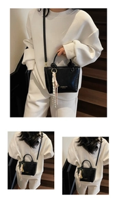 Detail of black glossy patent leather bucket bag with gold logo and woven tassel charm