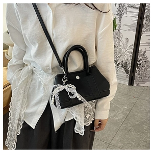 Détail du sac seau noir en cuir avec pendentif en perles et dentelle et fermoir argenté