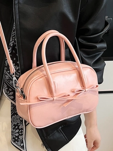 Sac Boston rose brillant avec nœuds, porté par un mannequin sur une veste en cuir