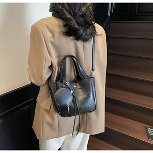 Détail du sac seau noir à texture crocodile avec un porte-monnaie rond amovible