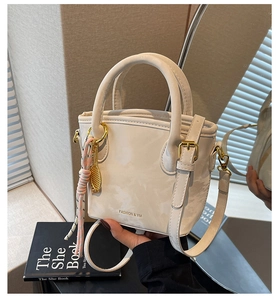 Detail of off-white bucket bag with marble texture, gold hardware and fashion charm