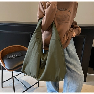 Dettaglio di una borsa tote verde oliva che mostra spalline larghe e trama del tessuto