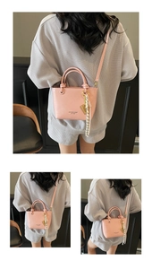 Pink glossy crossbody bucket bag shown with ribbon detail on a textured outfit