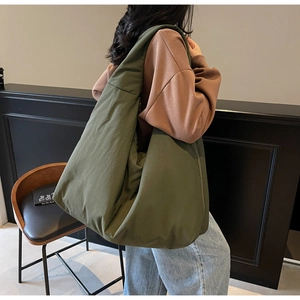 Grande borsa tote in nylon verde oliva indossata da modella in un ambiente casual