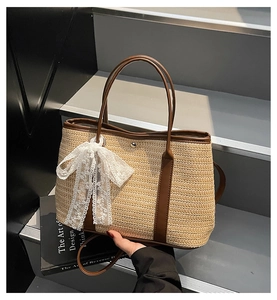 Détail d'un sac cabas en paille tissée avec garniture en cuir brun et nœud en dentelle