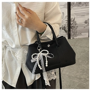 Détail d'un sac à main noir grainé avec un nœud en dentelle et perles raffiné