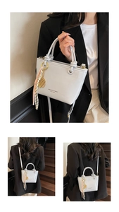 Close-up of light blue bucket bag with brand logo, pink tassel, and gold pendant details