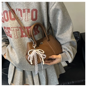 Sac seau marron en cuir avec pendentif élégant en perles et nœud en dentelle blanche