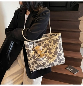Detailed view of large cow print tote bag featuring a cute brown bear sun charm