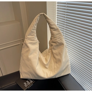 Dettaglio della borsa tote trapuntata beige con trama morbida e ampia tracolla larga