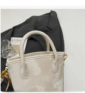 Close-up of beige leather bucket bag with marble texture and elegant gold hardware