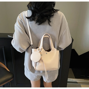 Détail d'un sac seau rose motif crocodile avec pochette ronde et pompon décoratif