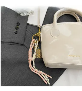 Detail of white leather bucket bag with braided cord charm and metal racket pendants