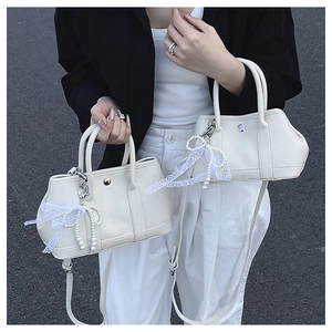 Détail de sac à main blanc en cuir grainé avec nœud en dentelle perlée et boucle
