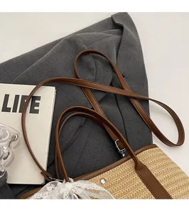 Détail du sac seau en paille montrant la bandoulière en cuir réglable et le nœud en dentelle