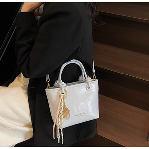 Detail of light blue bucket bag showing shiny leather texture and knotted handle