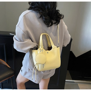 Détail du sac seau jaune à motif crocodile avec un petit porte-monnaie rond sur l'épaule