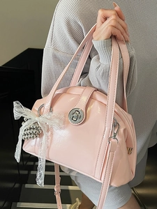 Sac coquille en cuir verni rose avec nœud en dentelle blanche et fermoir rotatif argenté