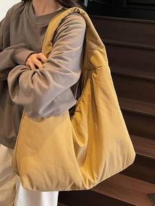 Borsa tote oversize minimalista in tessuto giallo zenzero indossata da una modella
