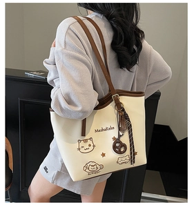 Detail of cream tote bag featuring cute cat embroidery and brown shoulder strap