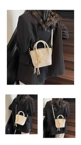 Detail of a creamy white bucket bag with elegant tassel and badminton racquet charm accessory