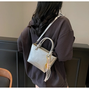 Detail of silver metallic crossbody bucket bag with decorative tennis racket charm