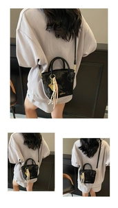 Detail view of black glossy bucket bag with silk scarf and gold brand lettering