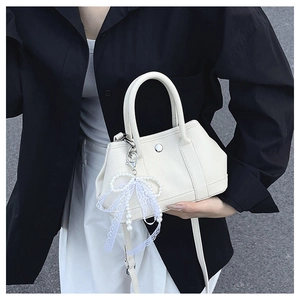 Détail du sac seau blanc à motif litchi avec pendentif perle et boucle en métal argenté