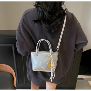 Close-up of silver metallic mini bucket bag with gold tennis racket charm detail