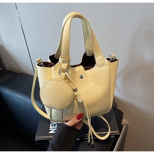 Détail du sac seau jaune crème avec motif crocodile et pendentif porte-monnaie rond