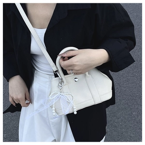 Détail du sac seau en cuir blanc crème avec élégant pendentif nœud en perle et dentelle