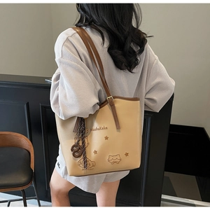 Detail of embroidered cat pattern and star logo on beige faux leather tote bag