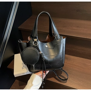Détail du sac seau noir à motif crocodile avec petit porte-monnaie rond attaché