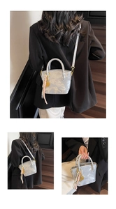 Detail of silver marble textured bucket bag featuring silk scarf and golden leaf pendant