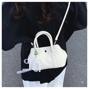 Détail d'un sac seau en cuir crème avec pendentif en perles et dentelle et bandoulière