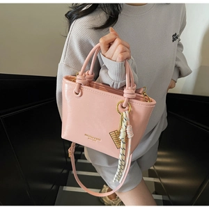 Close-up of pink leather bucket bag featuring gold brand logo and abacus charm detail
