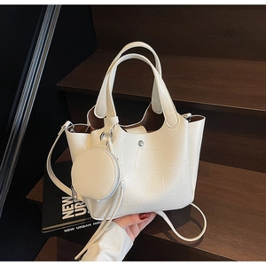 Sac seau blanc à motif crocodile avec bandoulière réglable et porte-monnaie sur un escalier