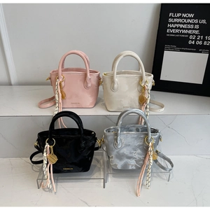 Detailed view of four colorful mini bucket bags with mesh charms and woven straps