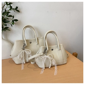 Détail de sacs seaux en cuir crème avec nœud en dentelle perlée sur bois naturel