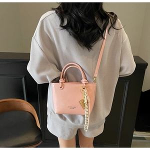 Detail of light pink tote bag with round handles, silk scarf, and gold charms