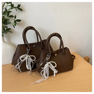 Détail de sacs cabas marron café avec texture litchi et pendentifs perles et dentelle