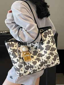 Retro cow print large tote bag with bear charm shown on a fashion model's shoulder