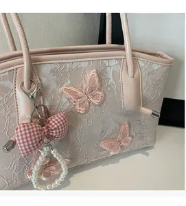 Detail of pink butterfly embroidery on lace fabric with pearl and ribbon charms