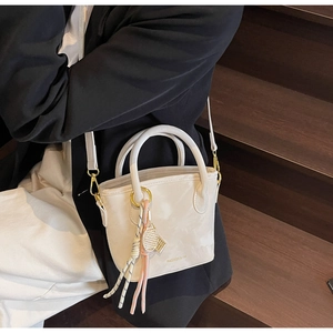 Detail of minimalist bucket bag with tennis racket charm and FASHION & YM logo