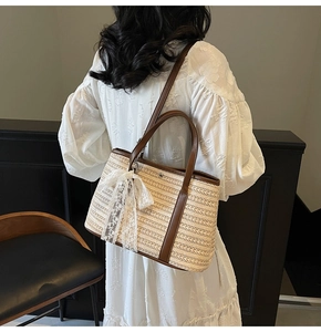 Détail d'un sac seau tressé avec des poignées en cuir foncé et un nœud en dentelle