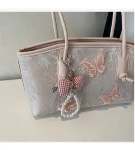 Detail of light pink tote bag with floral embroidery, 3D butterfly, and pearl charm